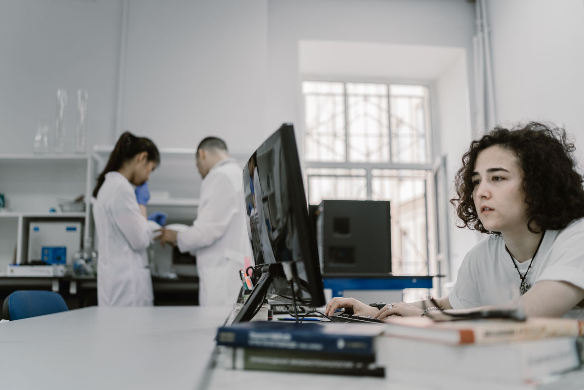 Analyst reviewing data on a computer screen in a busy research laboratory