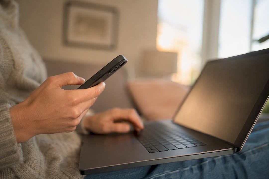 Une personne débranche son chargeur de téléphone posé à côté de son ordinateur portable.