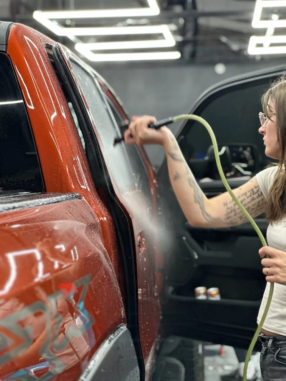 Technician steam cleaning the interior of a red Dodge Ram TRX door at Allure Auto Spa in Casselberry, Florida.