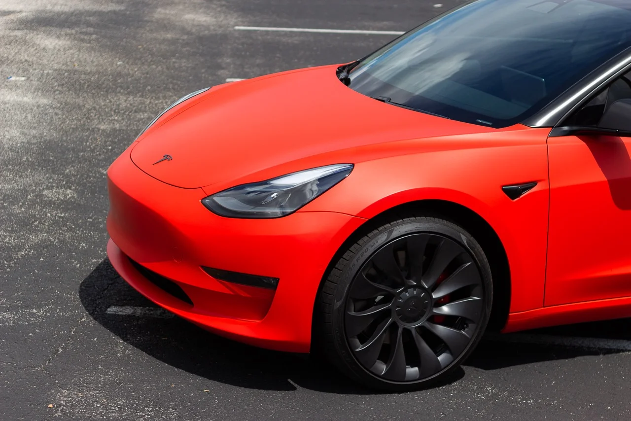 Front end of a red Tesla Model 3 showing precision window tint installation at Allure Auto Spa in Casselberry, Florida