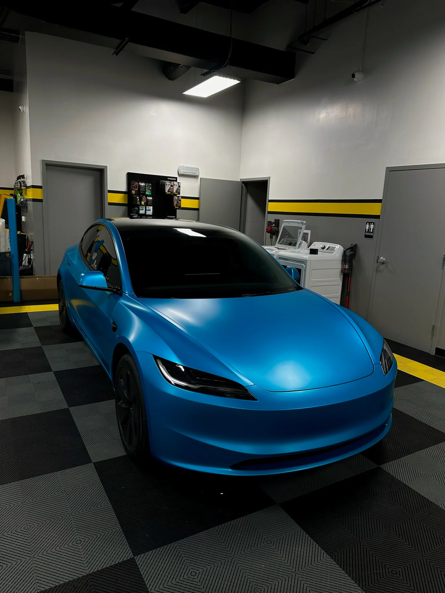 Tesla Model 3 with satin blue wrap and dark window tint parked inside Allure Auto Spa in Casselberry, Florida