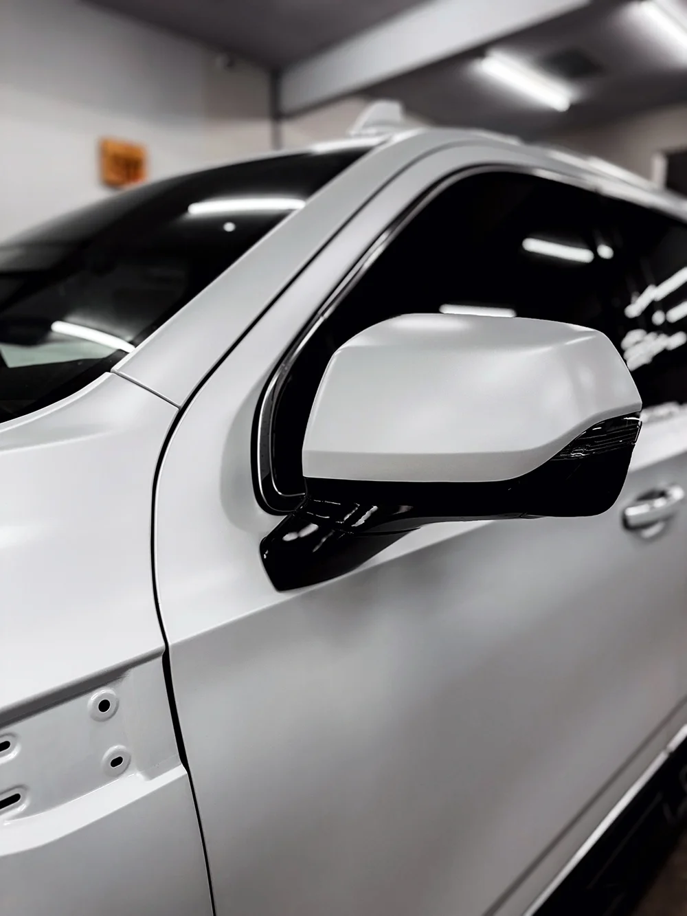 Detail shot of a white vehicle wrap on a GMC Sierra side mirror at Allure Auto Spa in Casselberry, Florida