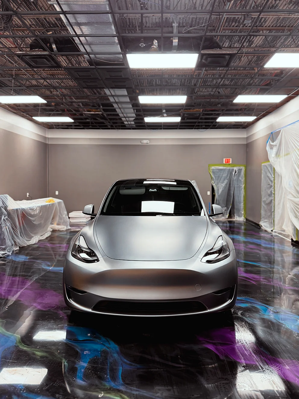 Front shot of satin-wrapped Tesla Model Y on colorful epoxy floor at Allure Auto Spa in Casselberry, Florida