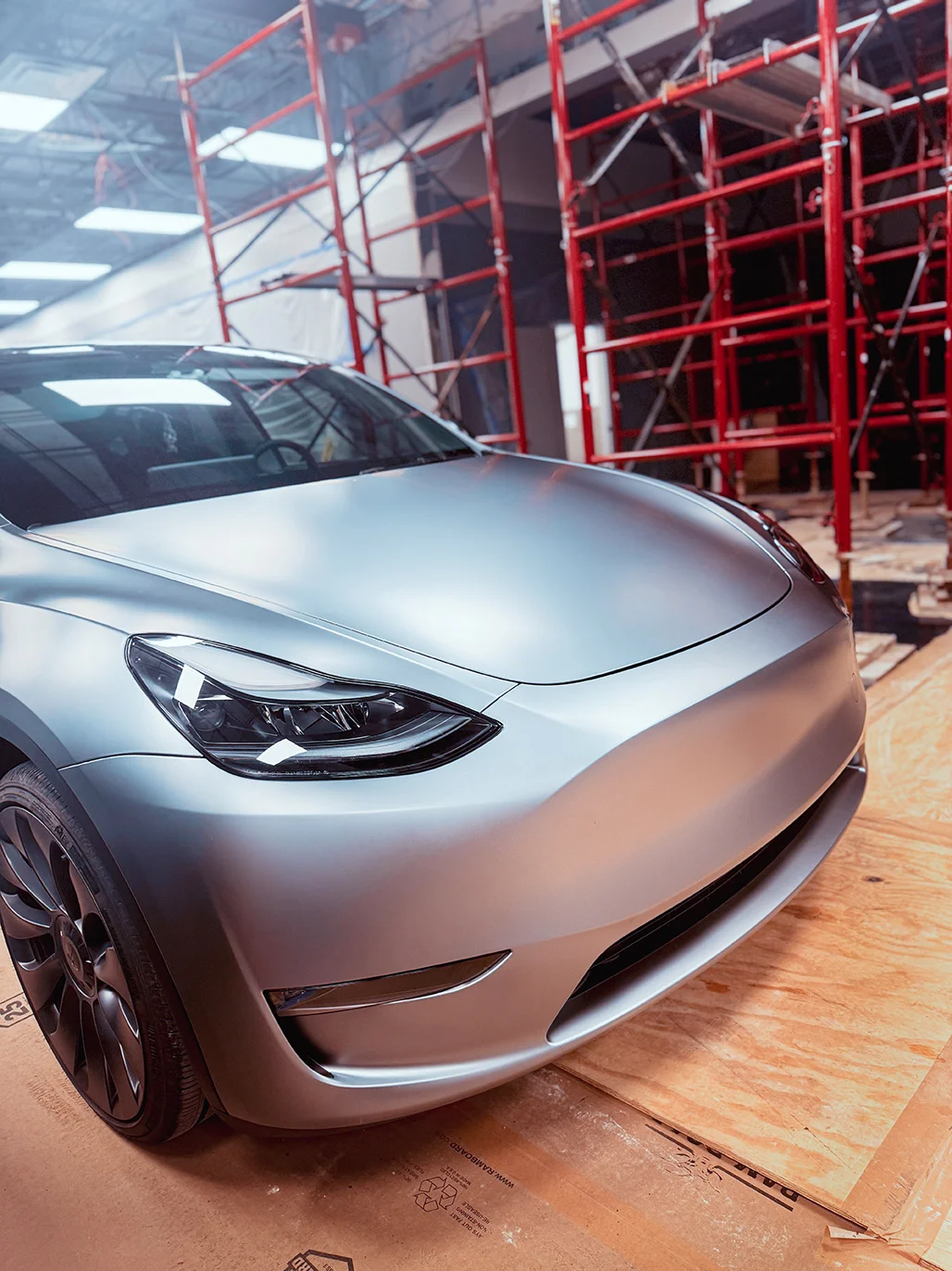 Tesla Model Y undergoing satin wrap installation surrounded by scaffolding at Allure Auto Spa in Casselberry, Florida
