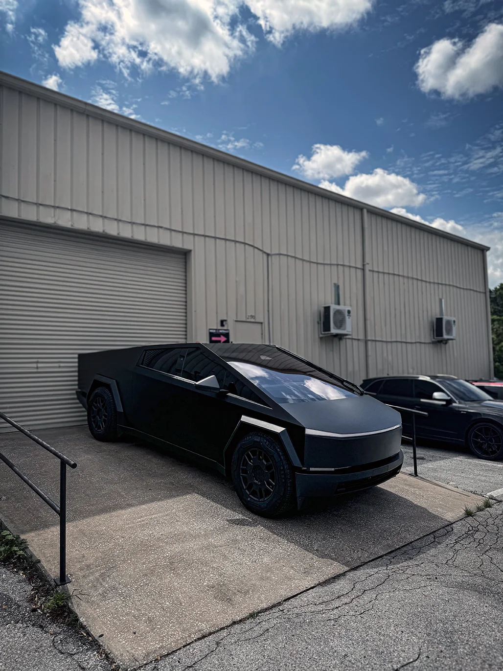 Impressive matte black vinyl wrap installed on a Tesla Cybertruck, parked outside Allure Auto Spa