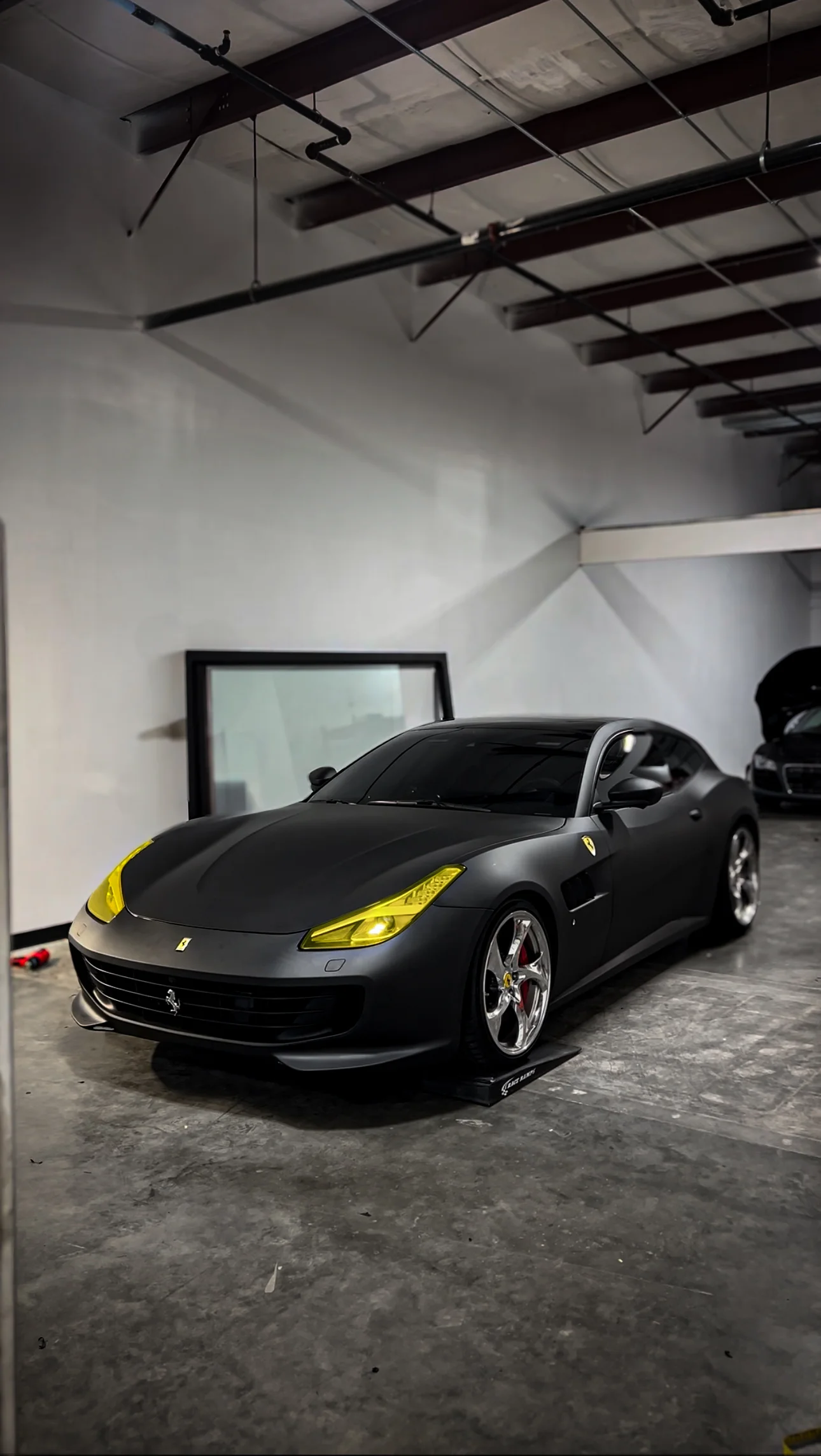 Sleek matte black car wrap with yellow headlight tint on a Ferrari GTC4Lusso, a custom vehicle transformation by Allure Auto Spa
