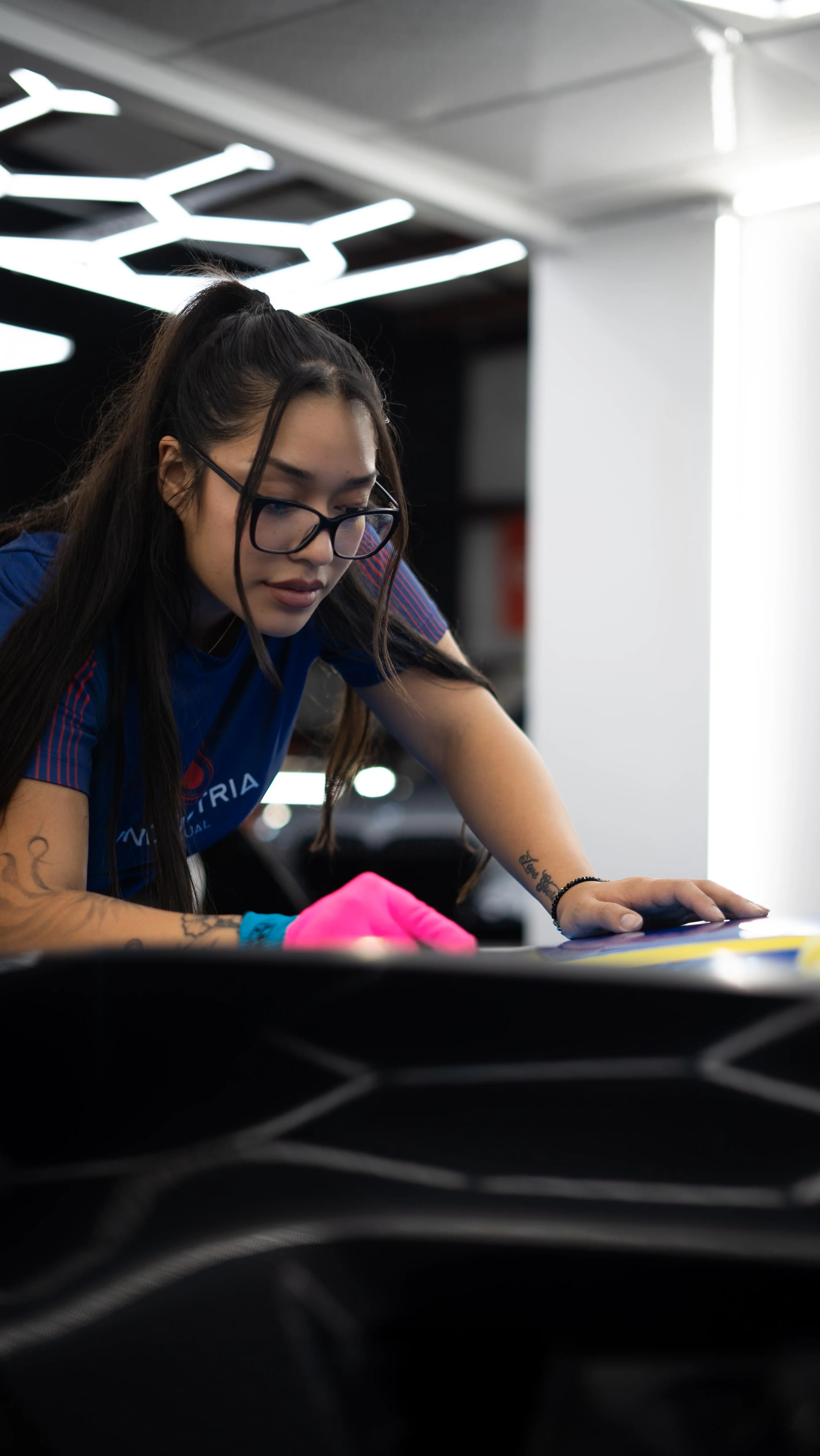 A female technician from Allure Auto Spa meticulously working on the detail of a car wrap for a Chevrolet Corvette C7
