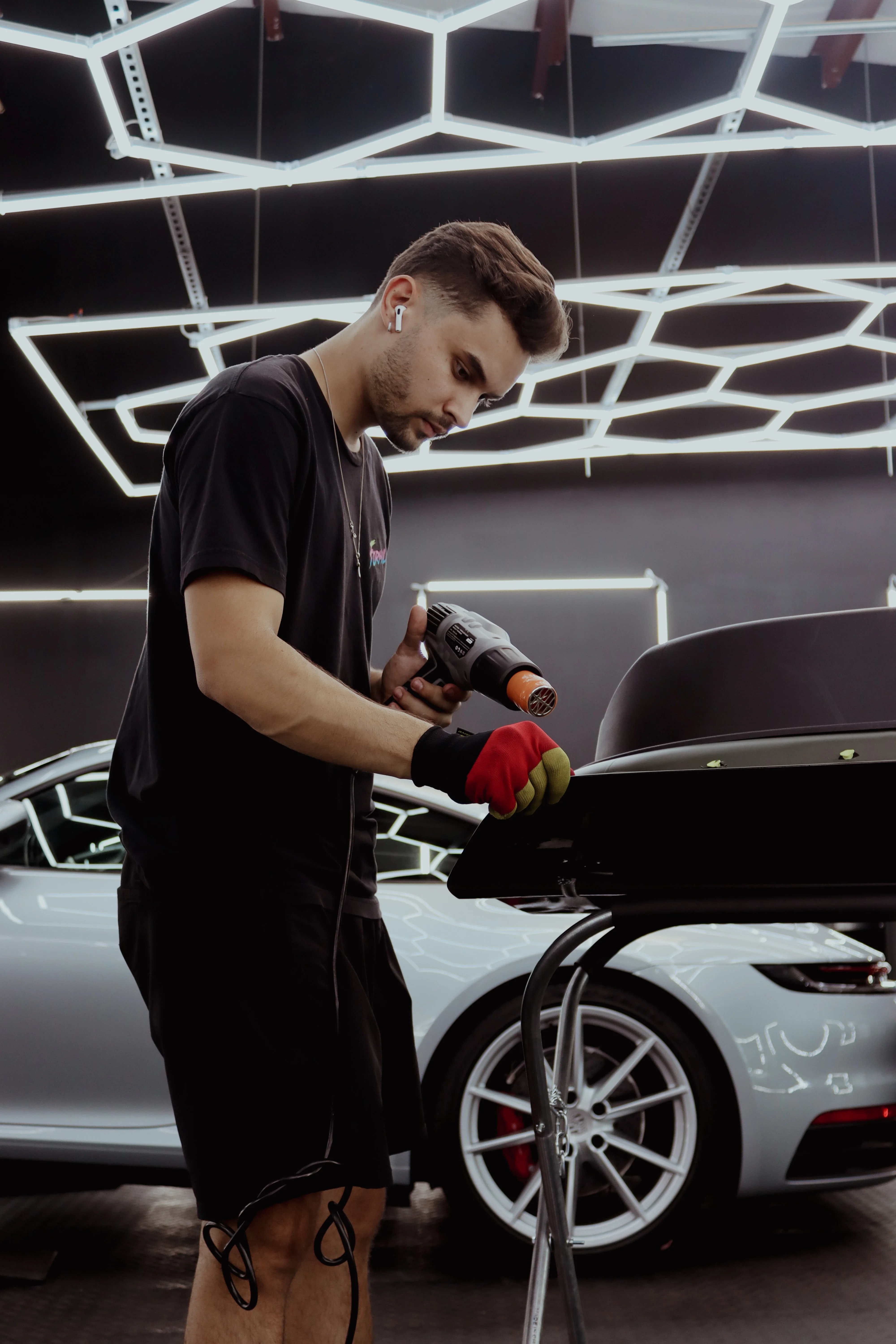 Skilled technician applying heat to shrink and secure a car wrap on a Porsche 911 at Allure Auto Spa's facility