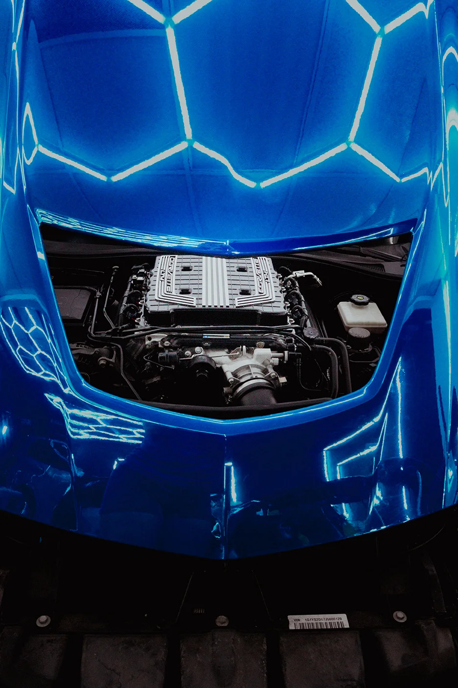 Overhead view of a Chevrolet Corvette C7 Z06 engine bay, perfectly framed by a high-gloss blue custom car wrap by Allure Auto Spa