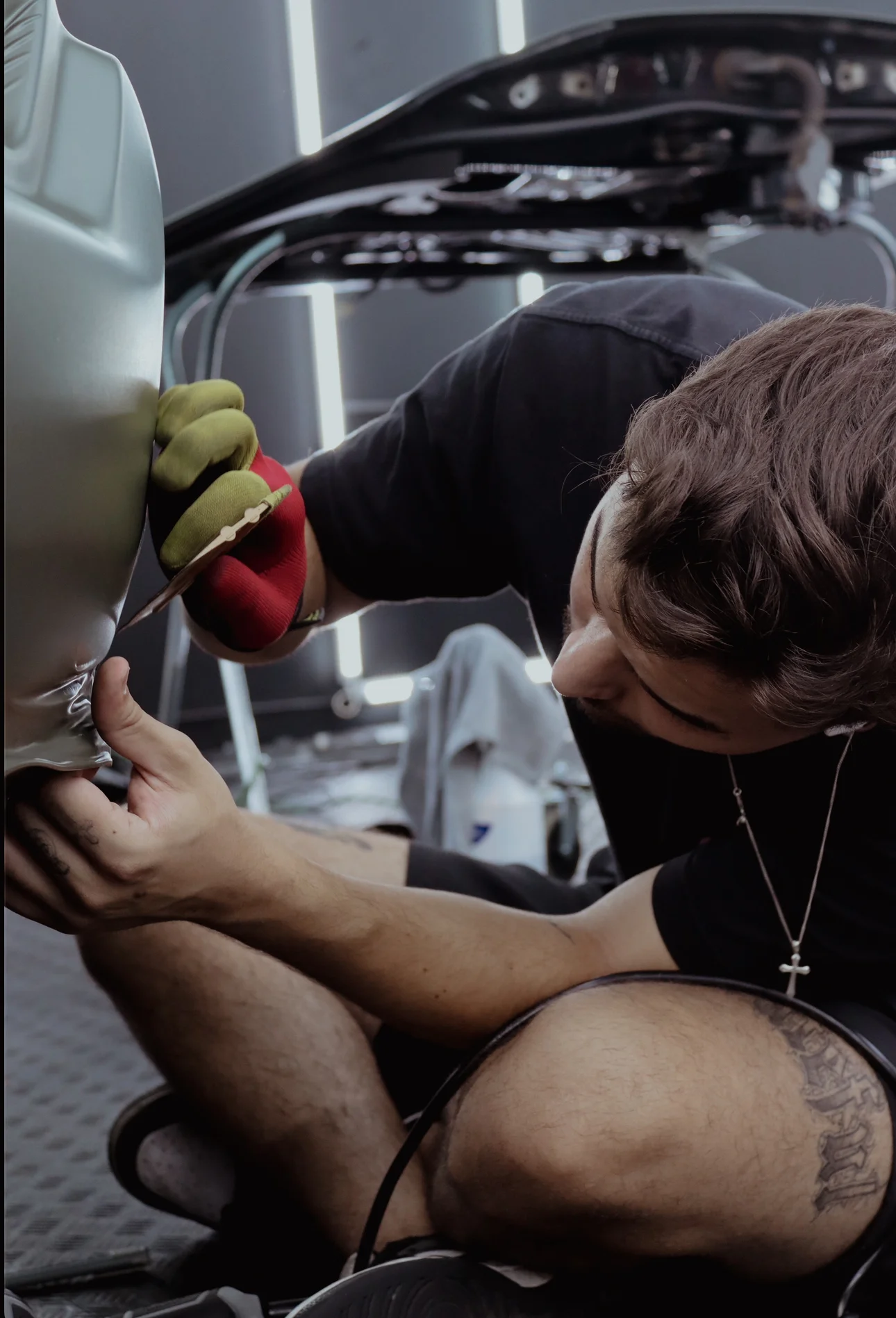 Allure Auto Spa technician precisely trimming excess vinyl during a car wrap installation on a Tesla Model S