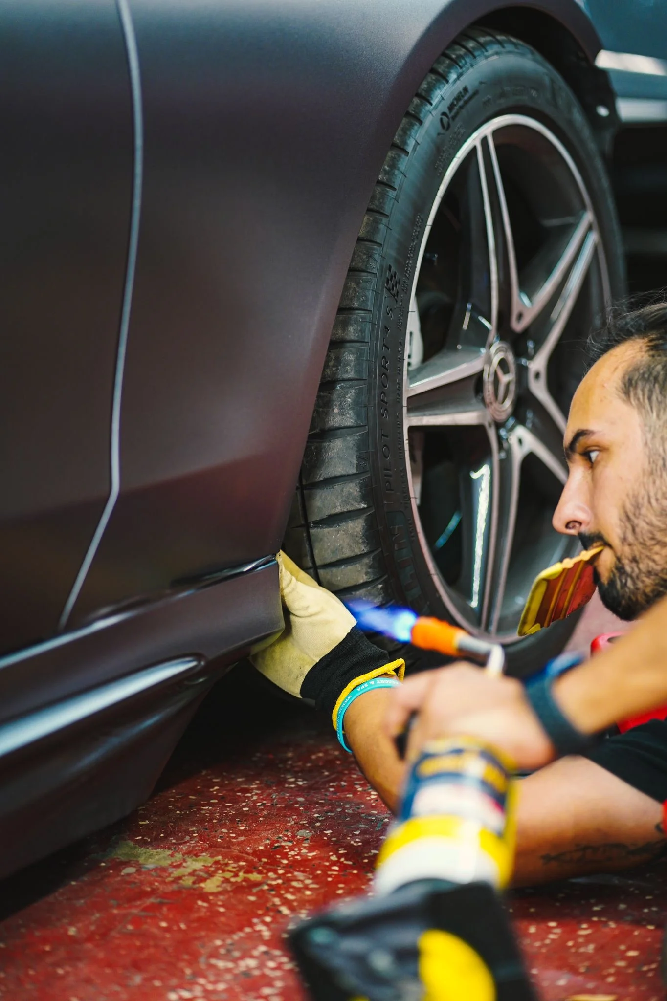 Allure Auto Spa technician using a heat gun for precise application of a matte black car wrap on a Mercedes-Benz coupe