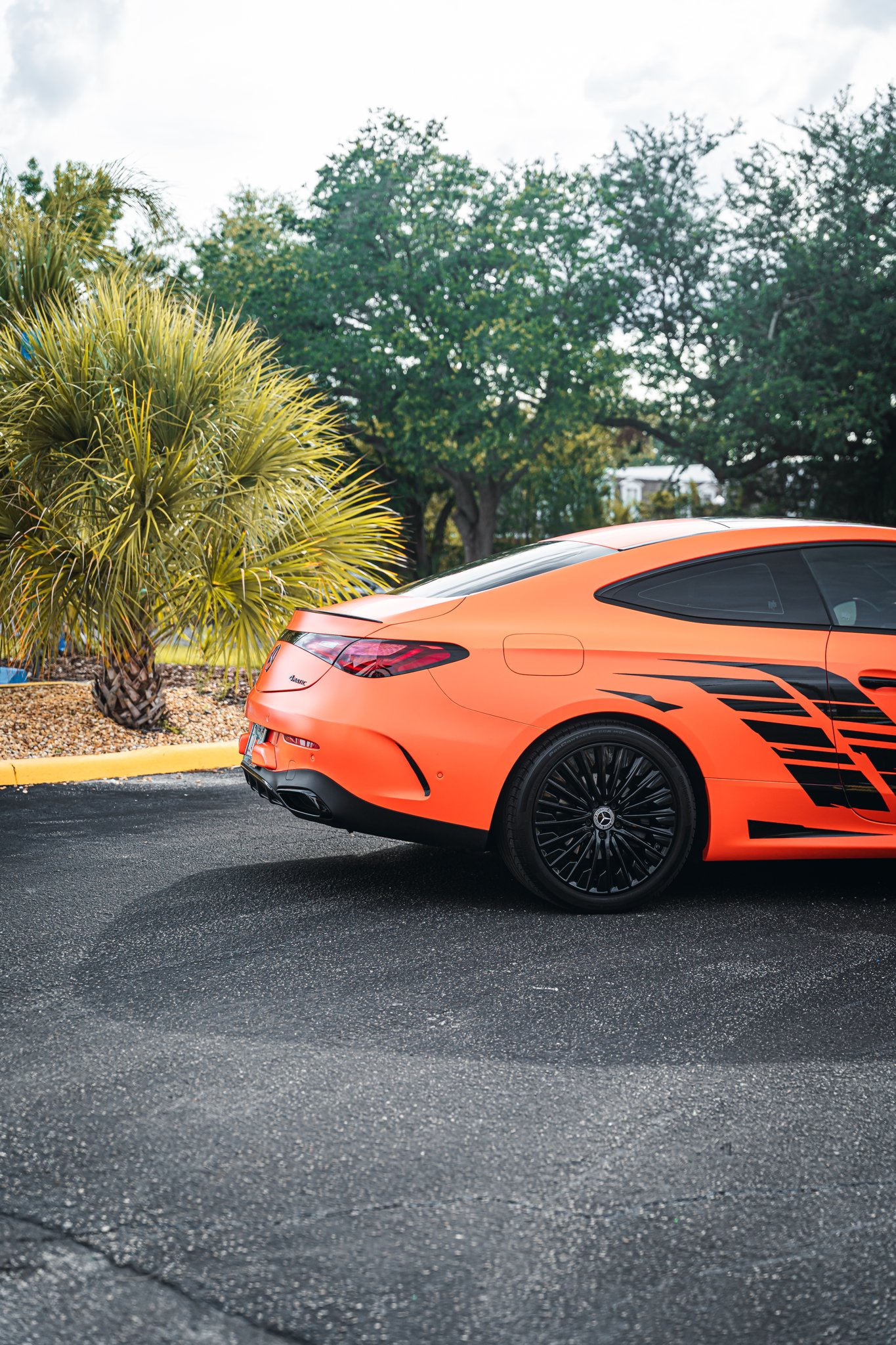 Rear view of a matte orange color-change wrap with black graphics on a Mercedes coupe