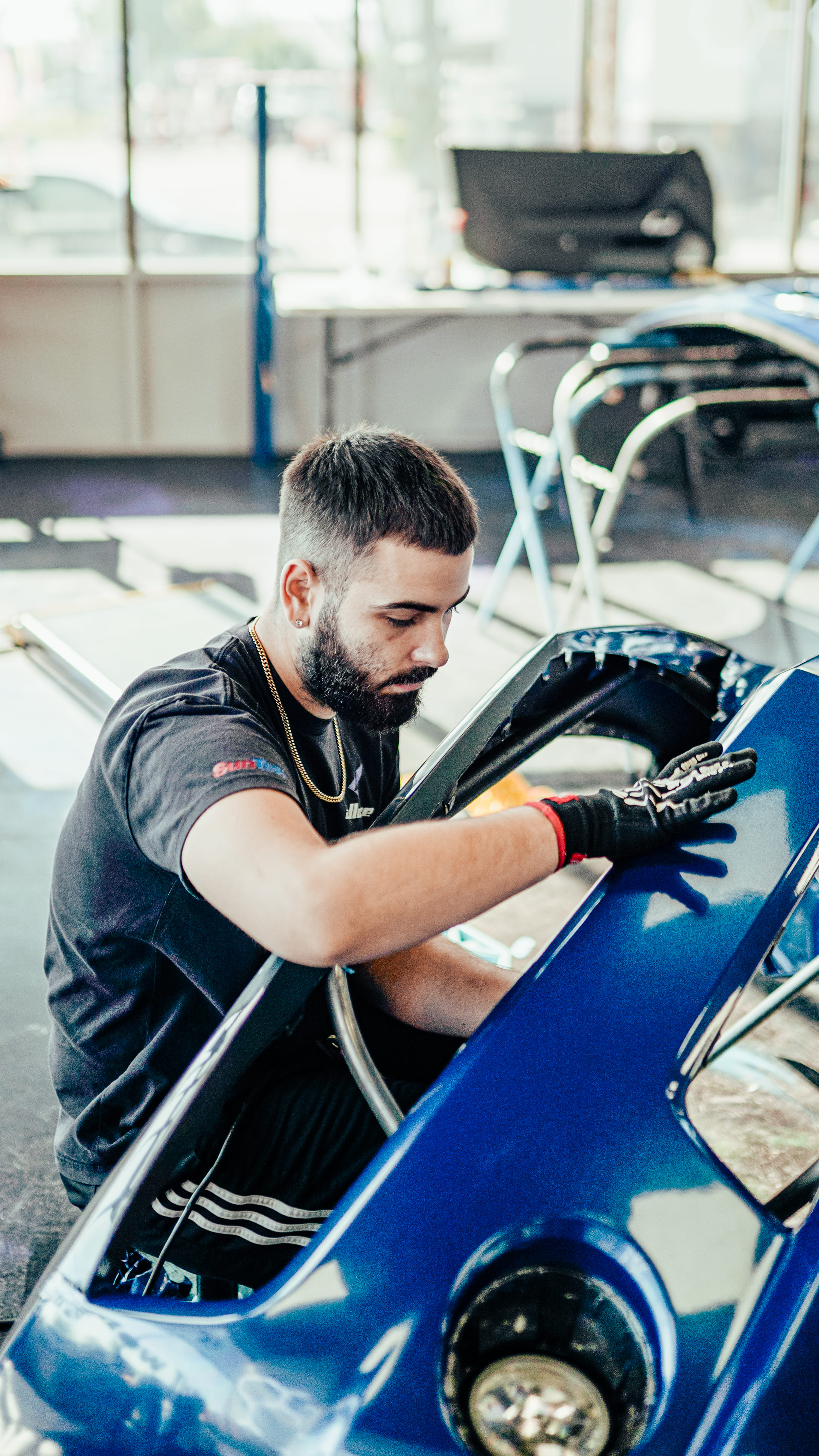 Installer applying a vinyl color-change wrap to a car panel at Allure Auto Spa, FL