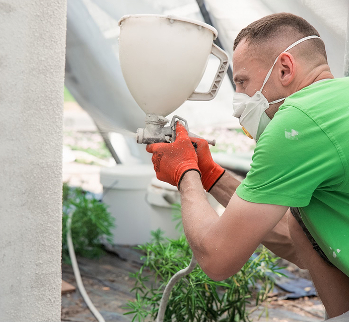 Aanbrengen van spuitkurk op een gevel tijdens gevelrenovatiewerken.