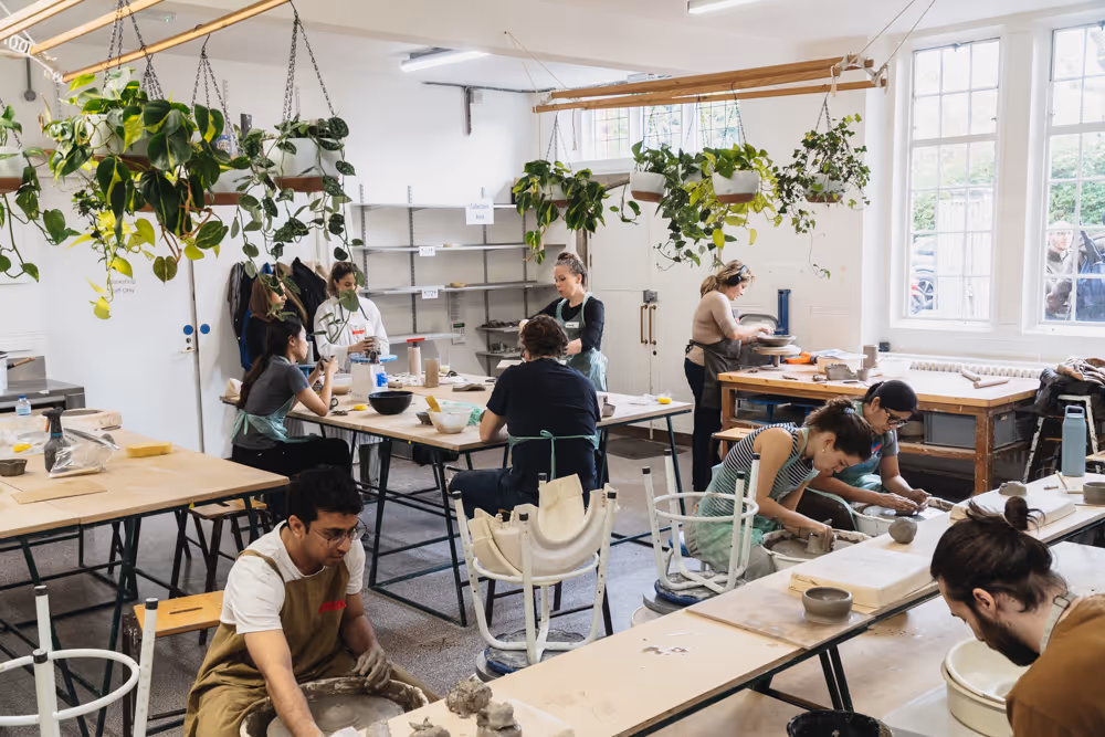 A pottery class working at long benches in the Turning Earth studio