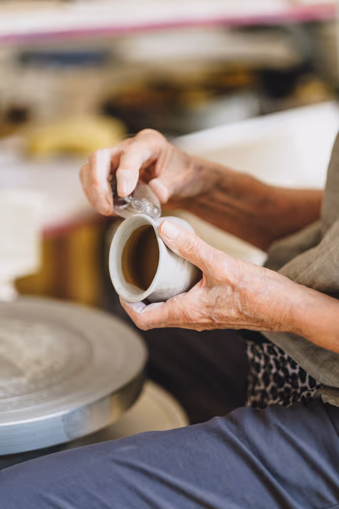 Person shaping clay on a pottery wheel