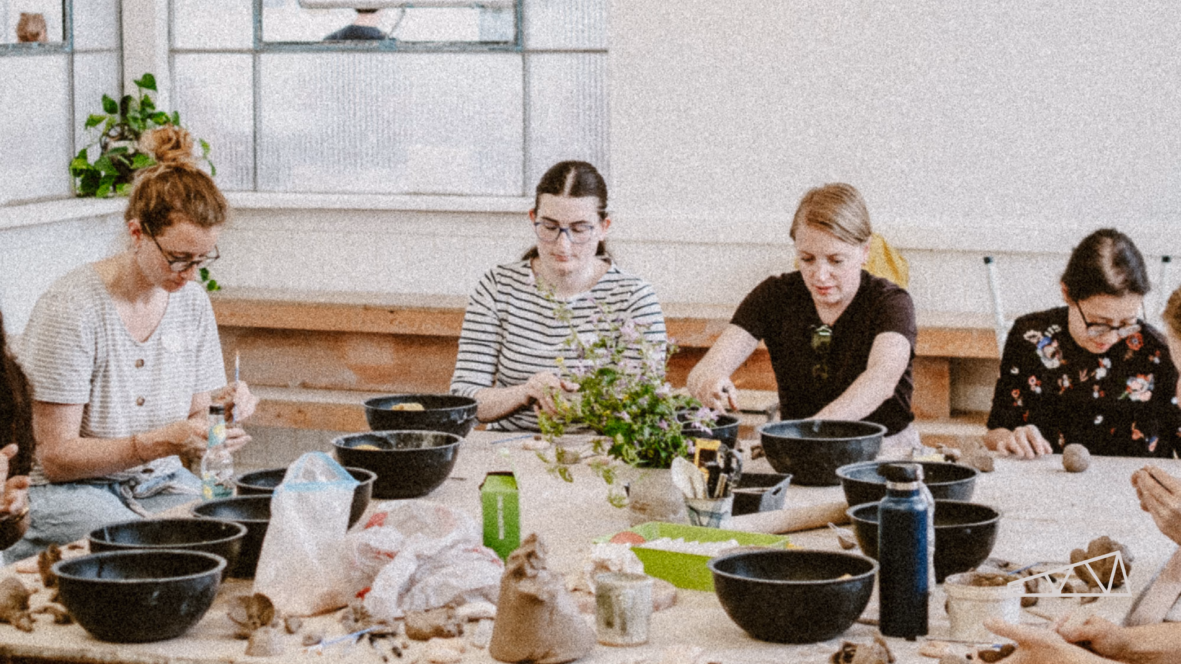 The Learning Hub classroom at Turning Earth Leyton pottery studio, with wooden worktables and hanging plants