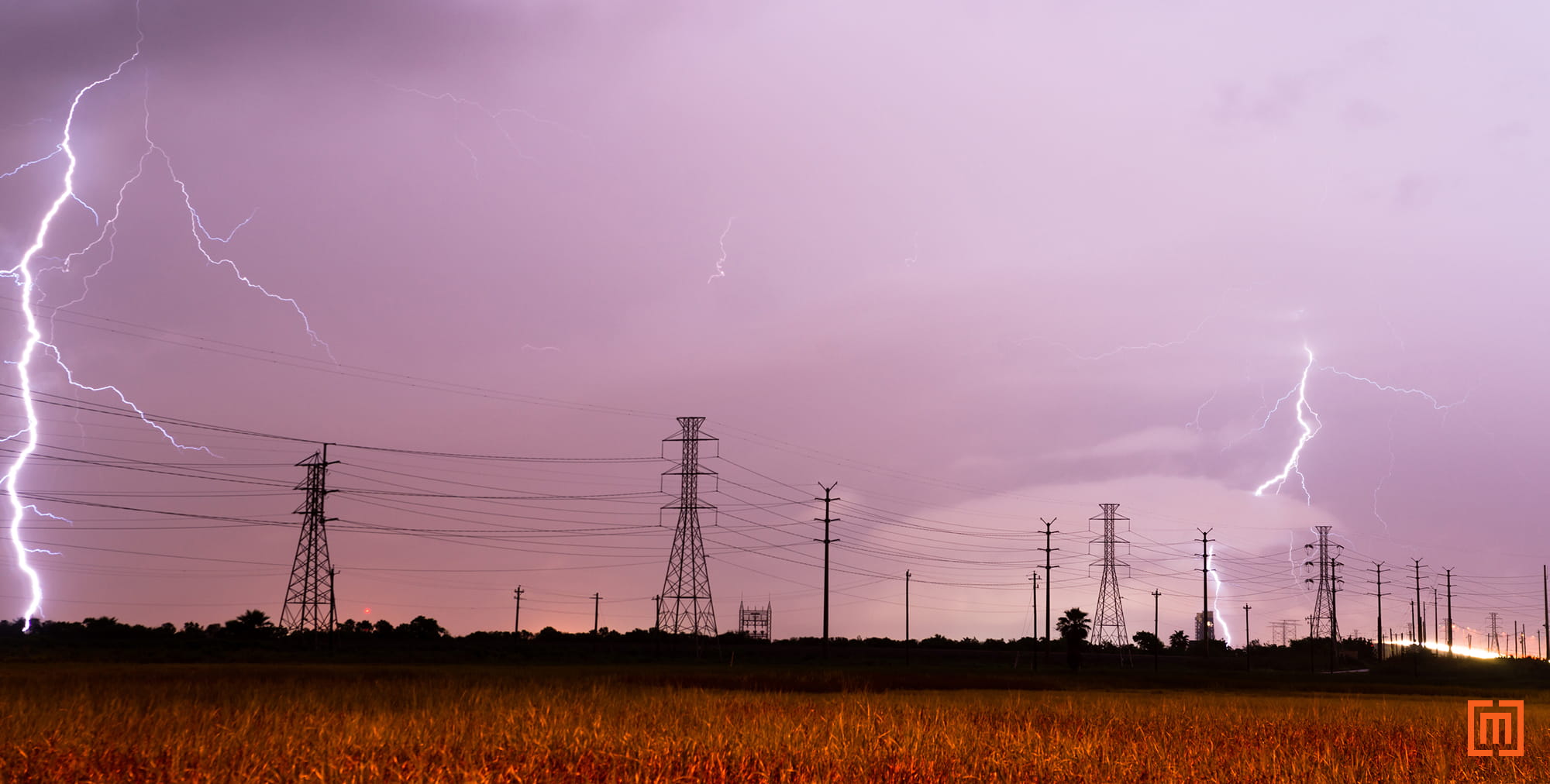 photo of lightning around power lines against a purple sky