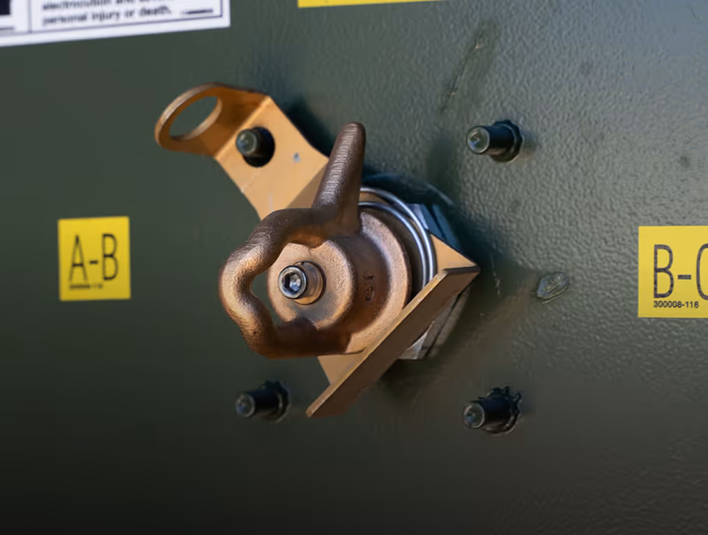 Close-up of a brass control valve with a metal ring on dark painted equipment labeled to vent tank.