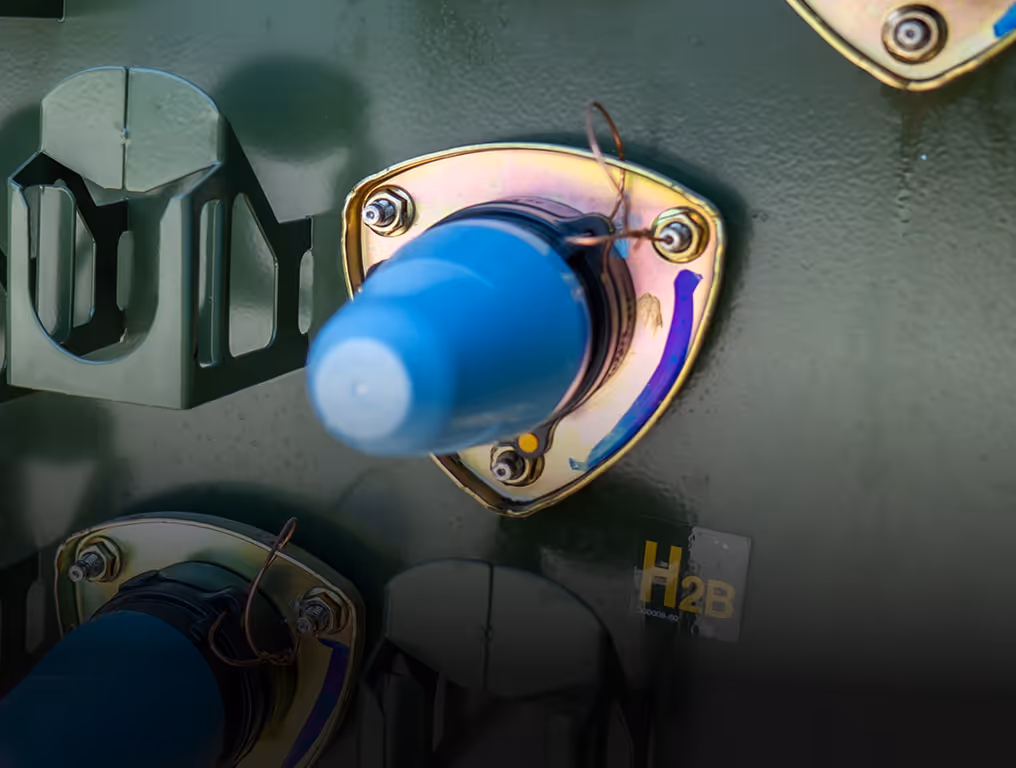 Close-up of blue electrical transformer parts mounted on a green metal panel with connectors and labels.
