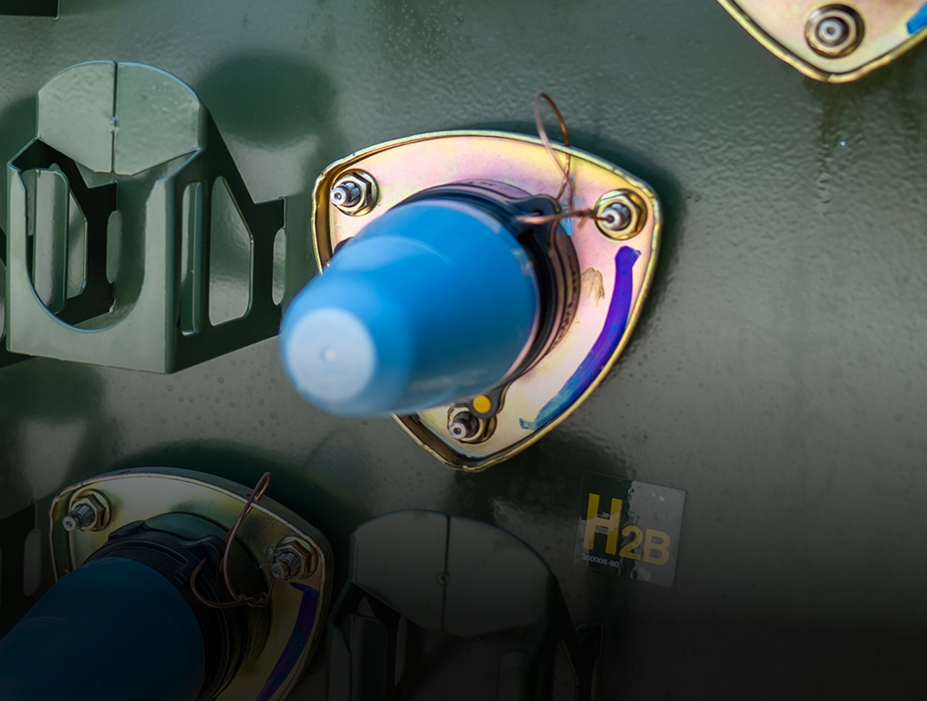 Close-up of blue electrical transformer parts mounted on a green metal panel with connectors and labels.