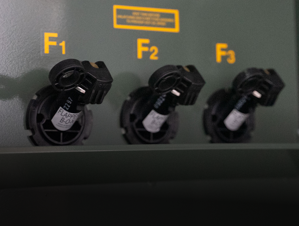 Three black plastic knobs labeled F1, F2, and F3 on a green panel with yellow lettering.