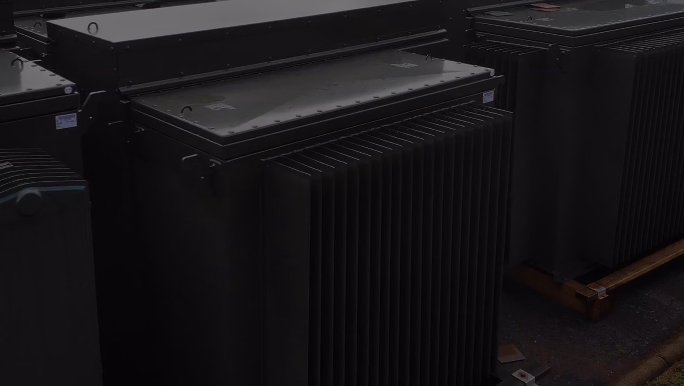 Large pad mounted transformer with cooling fins arranged outdoors on a concrete surface.