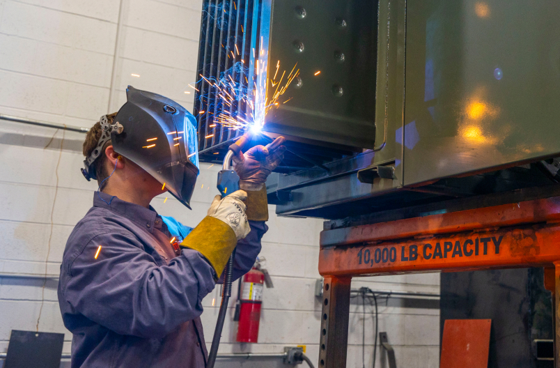Technician welding a custom transformer