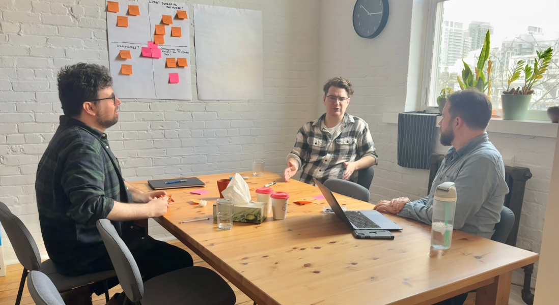 Coworkers chat surrounded by post-it notes and laptops
