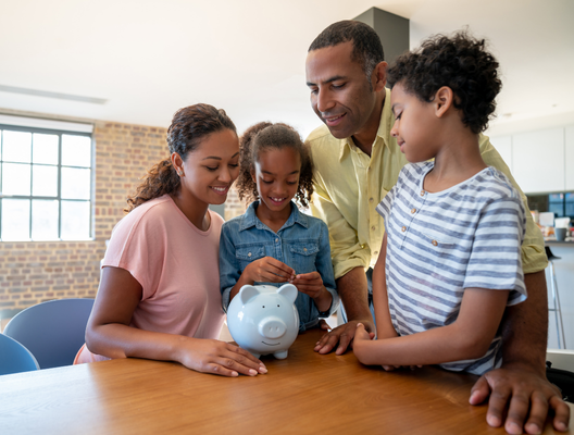 A family of four is saving money together in a piggy bank