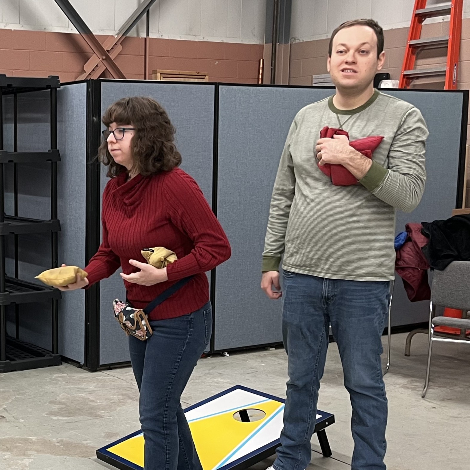 Two people are playing cornhole indoors at Disability Network Eastern Michigan's Troy location.
