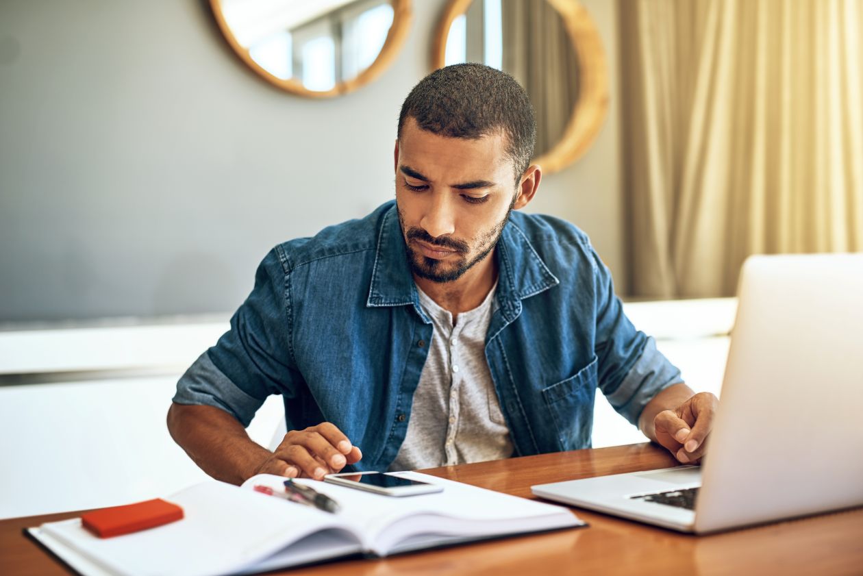 Man looking at his phone an laptop
