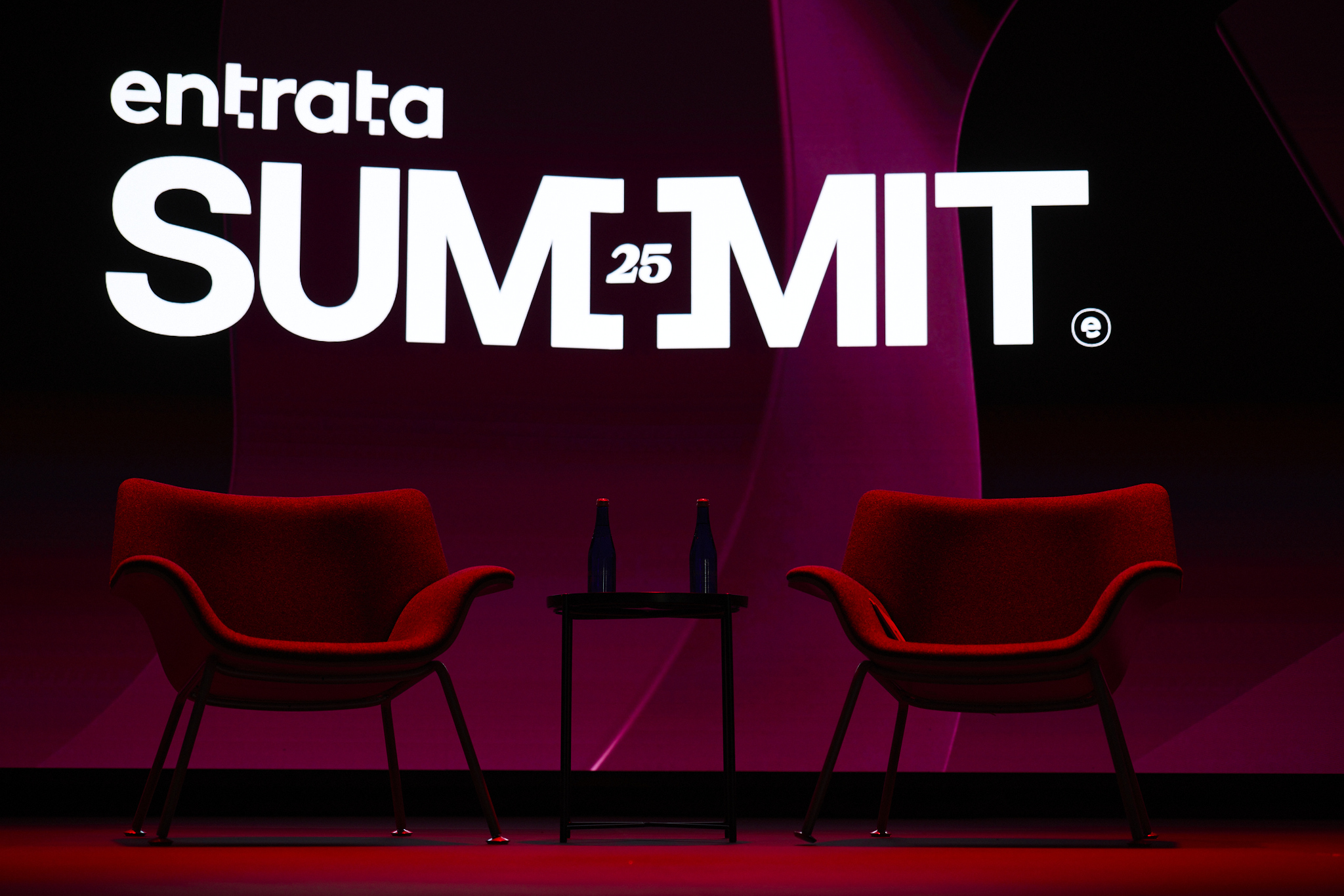 Two empty red chairs in front of a Summit sign