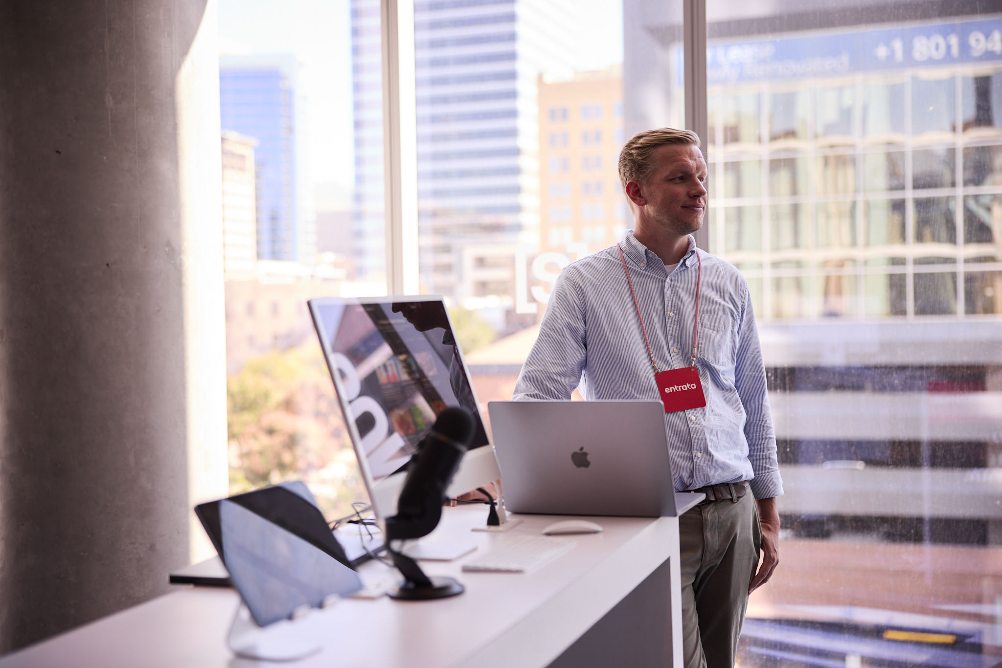 Man with an "Entrata" badge standing next to some computers