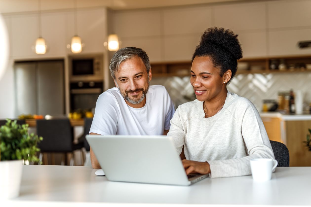 A man and woman smiling at a computer