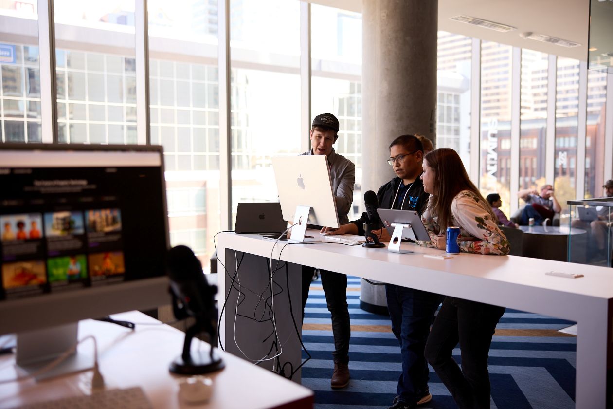 Three people looking at a computer in a hotel lobby