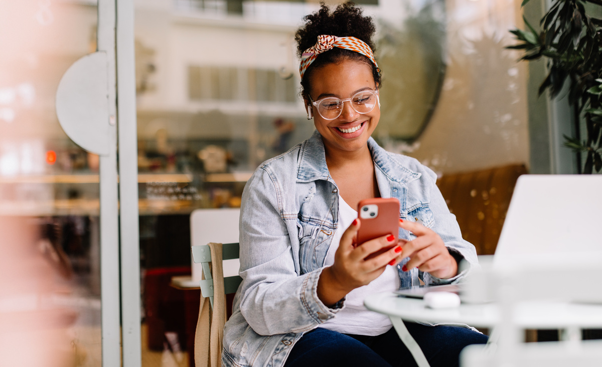 A woman sitting at a white desk smiling at her phone