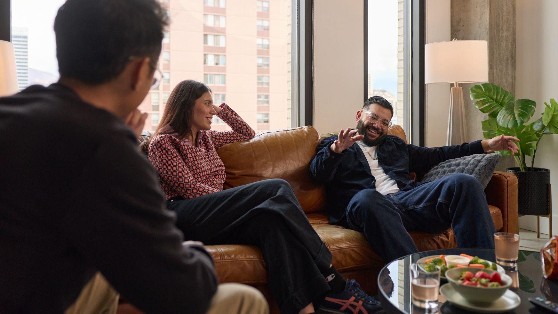 three people sitting in a living room having a conversation and laughing
