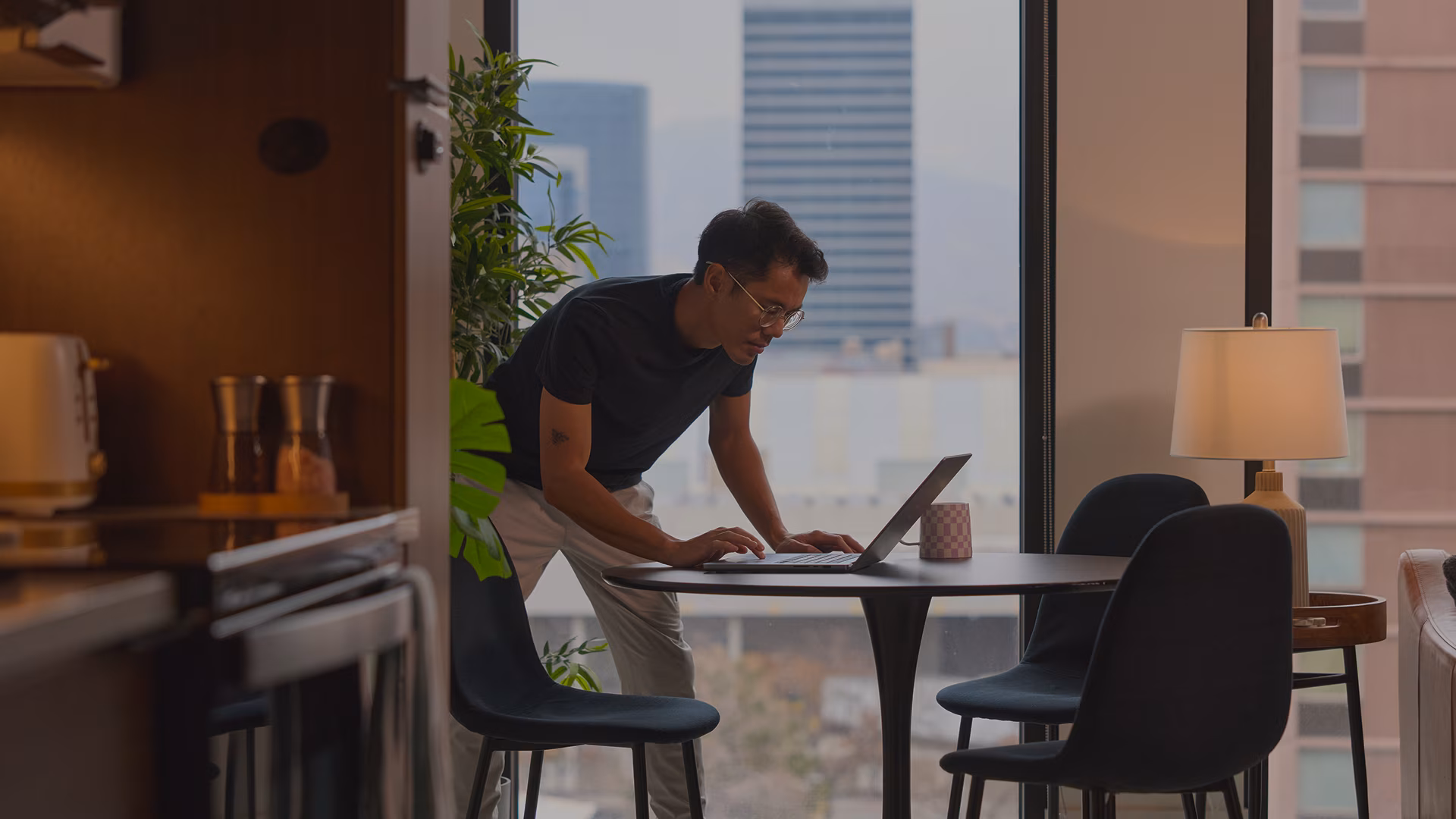 Man scrolling his computer while standing in his home