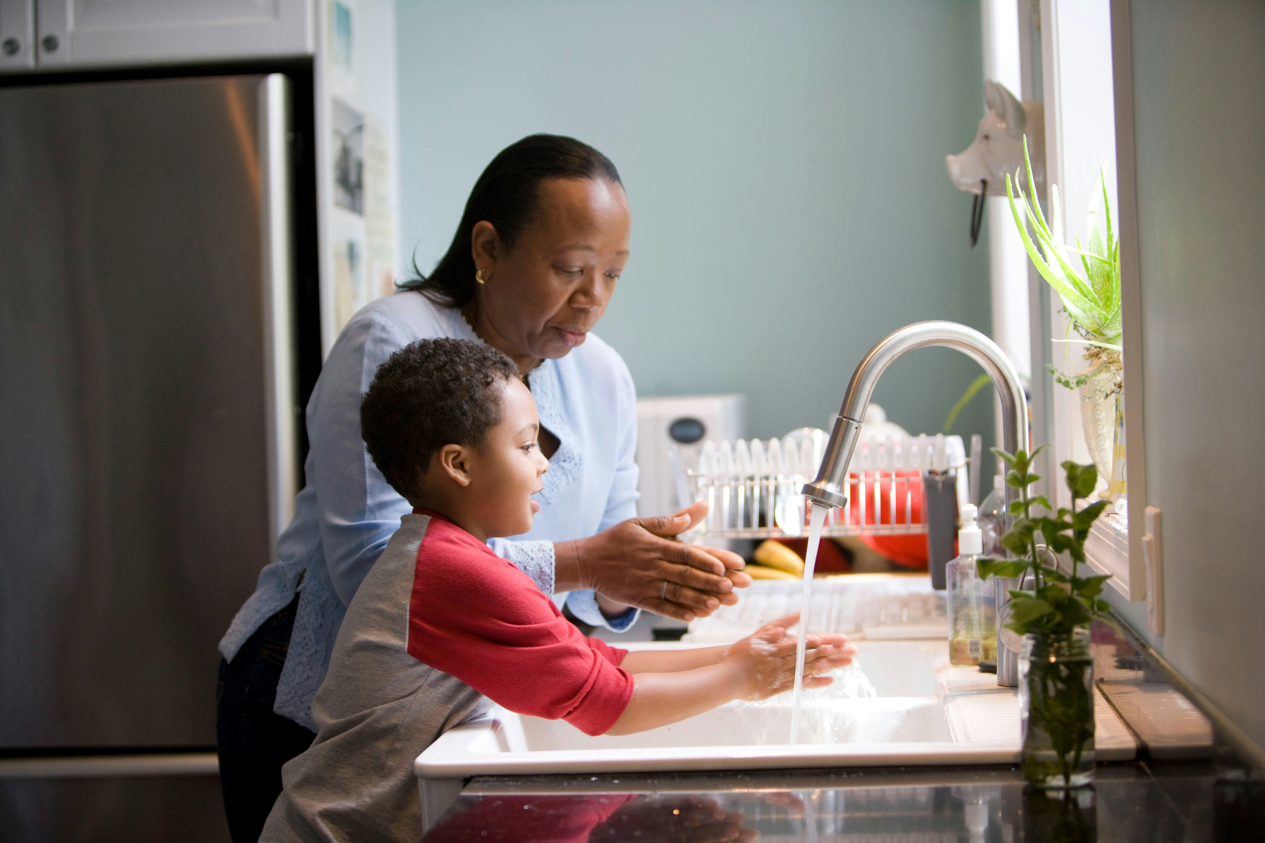 An older woman and a child in the kitchen cleaning dishes
