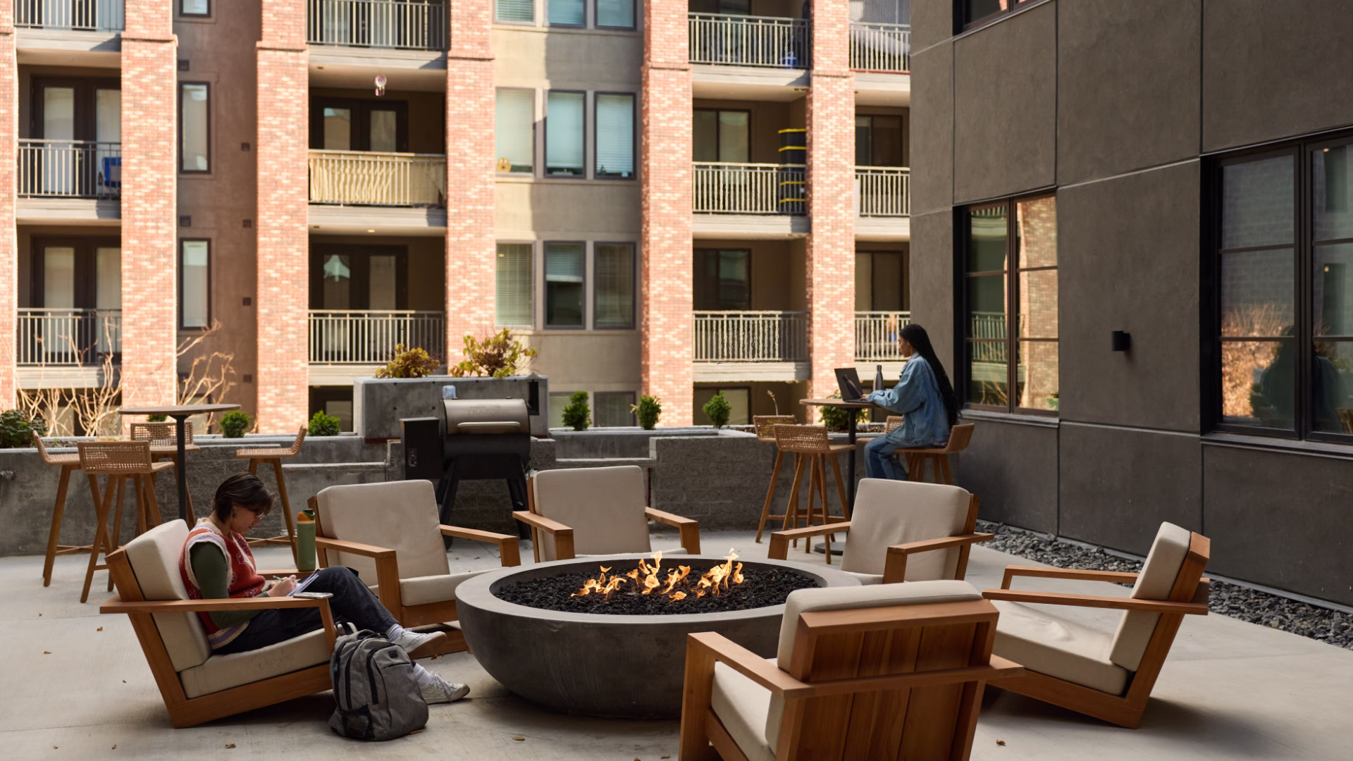 an outdoor communal patio with chairs, a fire pit, and tables