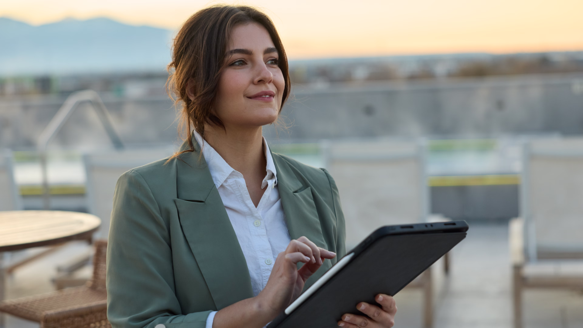 A leasing agent outside on a rooftop patio holding a tablet