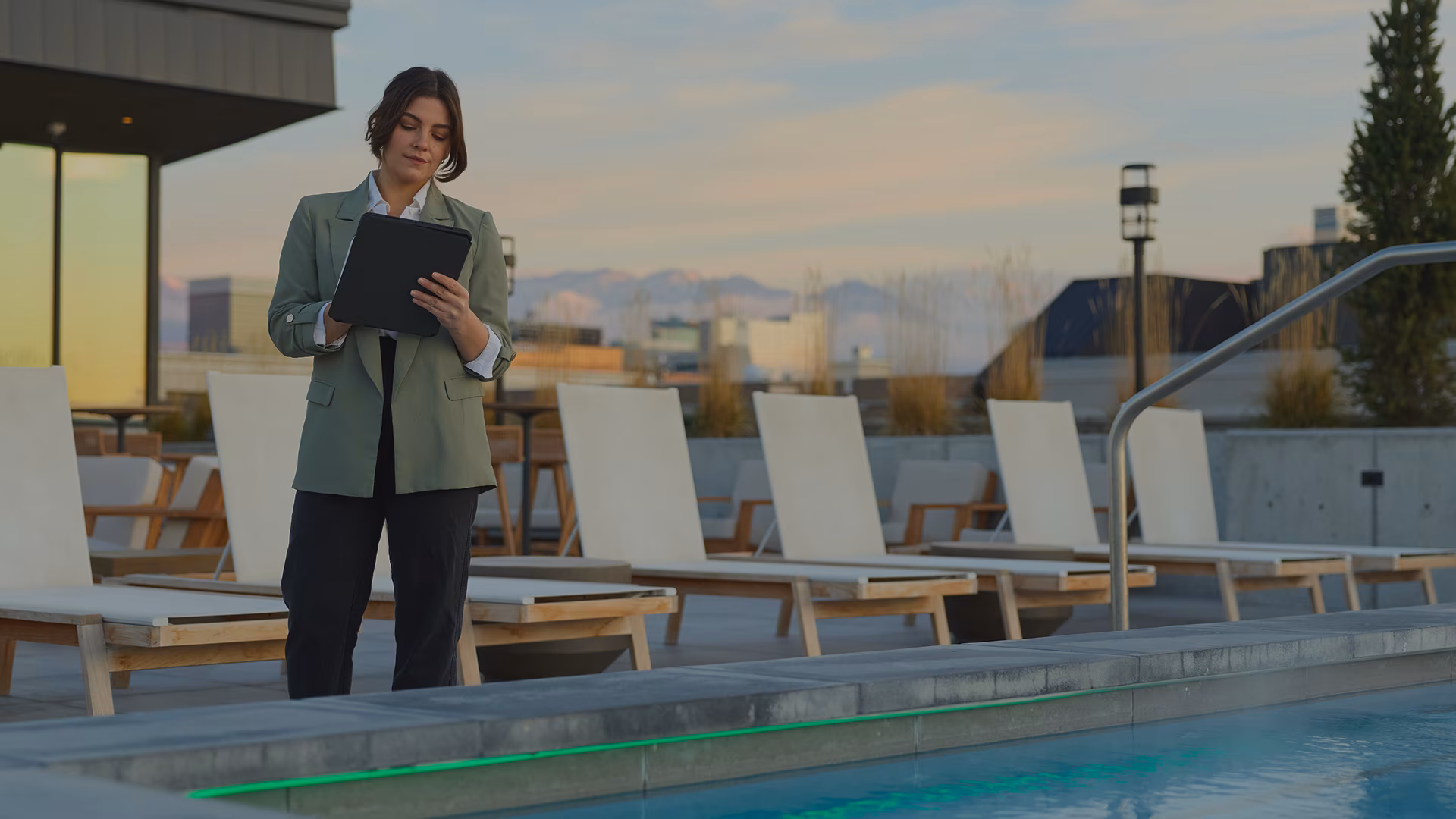 Woman standing next to pool working on a tablet