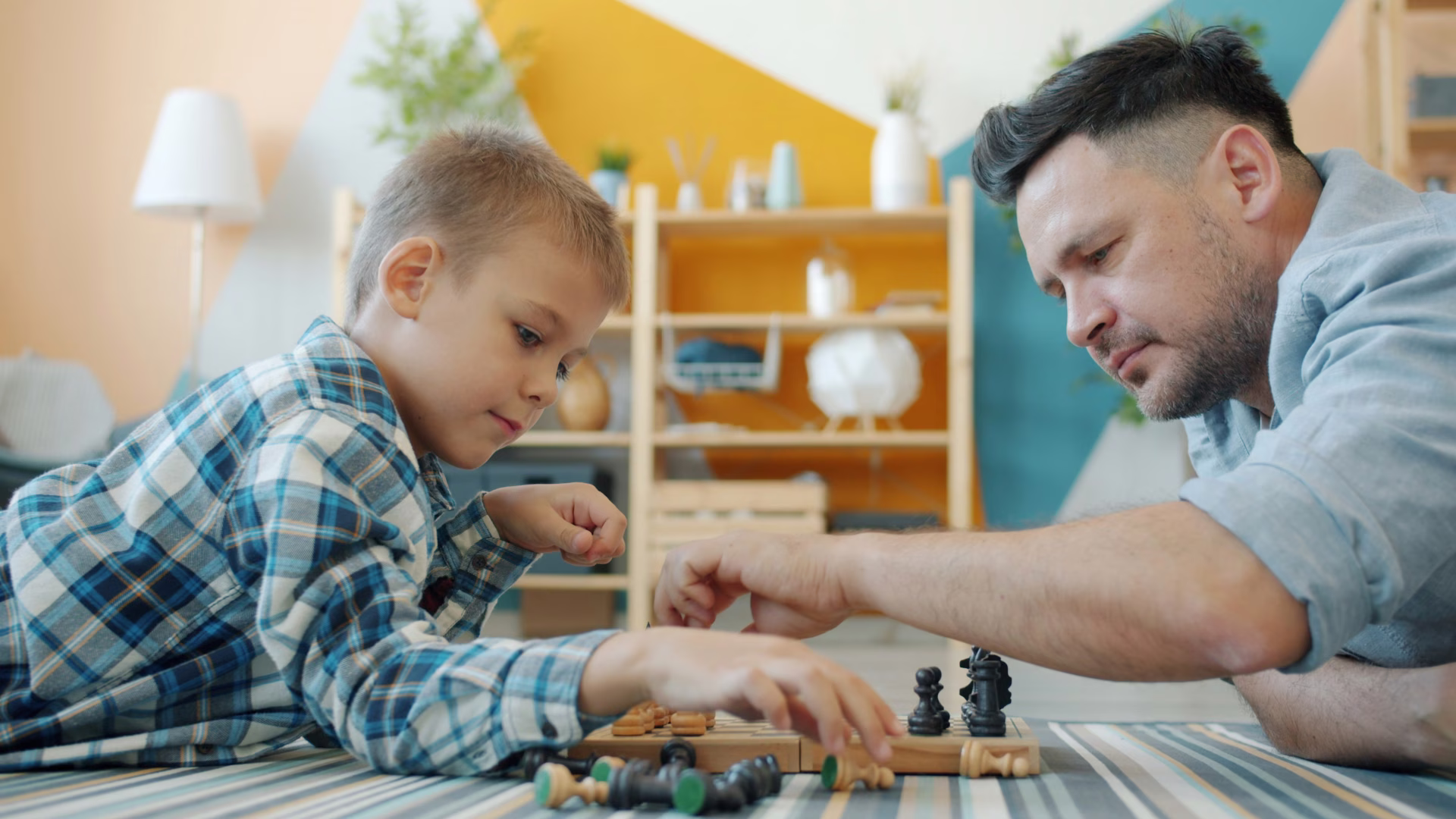 A father and his son playing with toys on the floor in a brightly lit living room