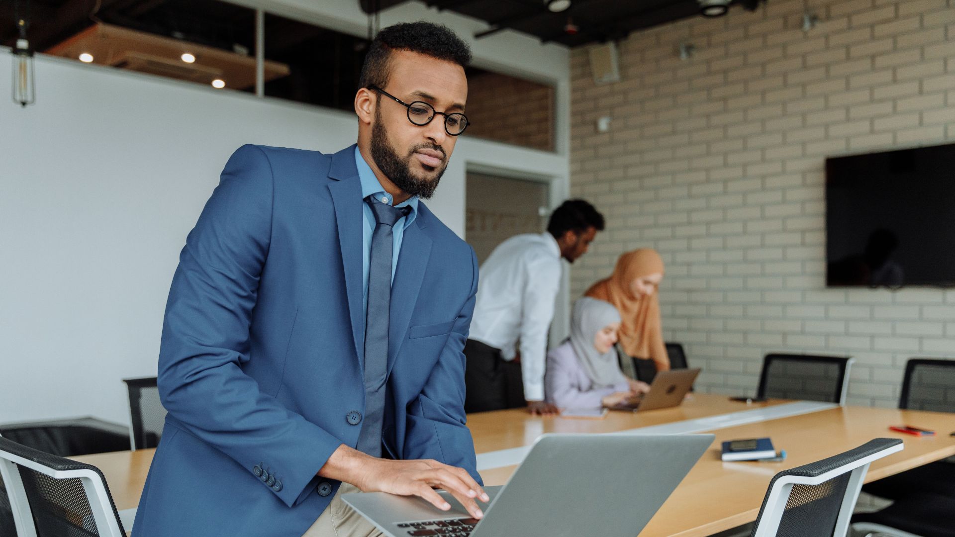 A man in a blue suit works on a laptop.