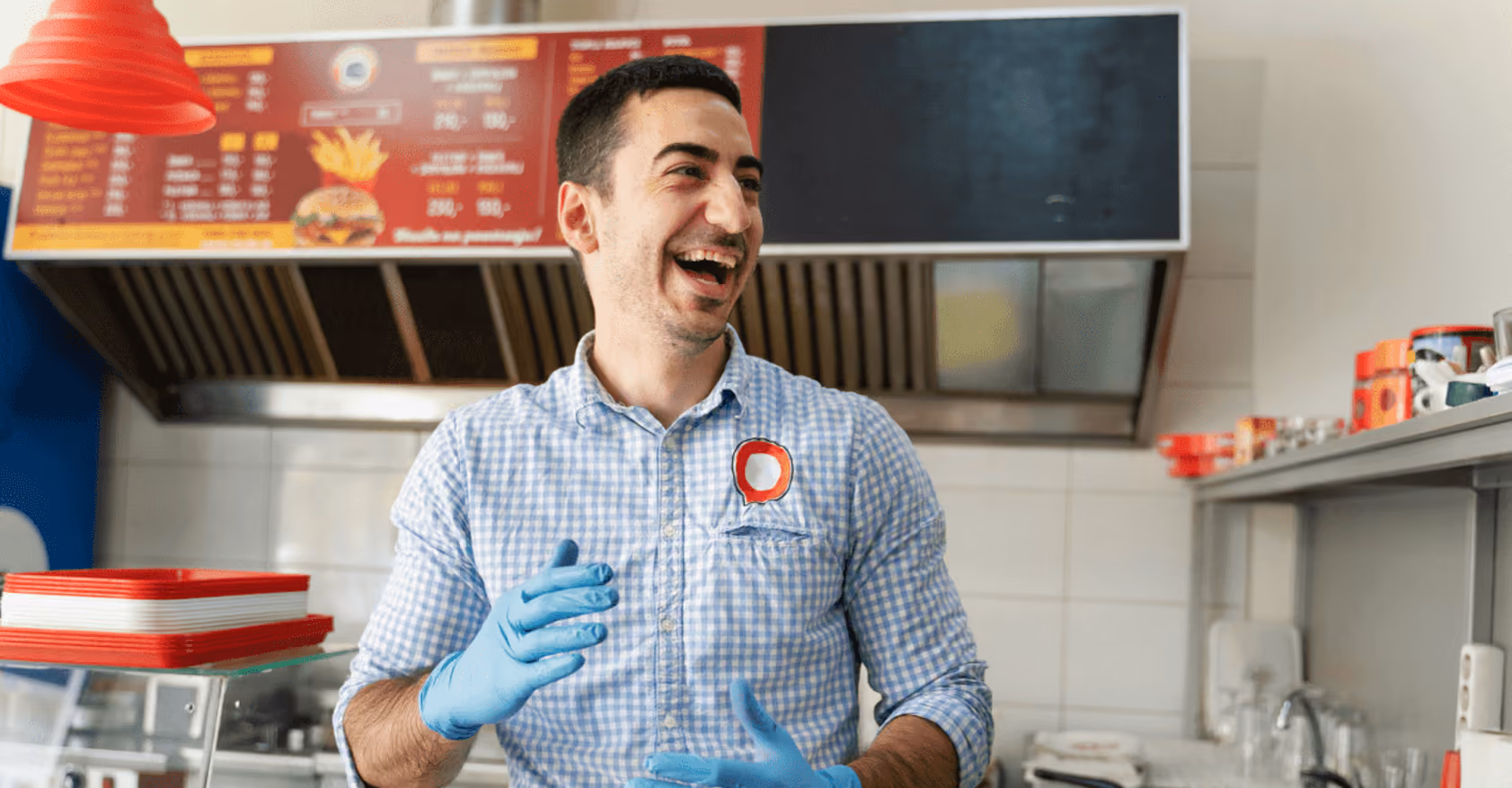 A man wearing gloves holds a tray of food while standing in a restaurant setting. 