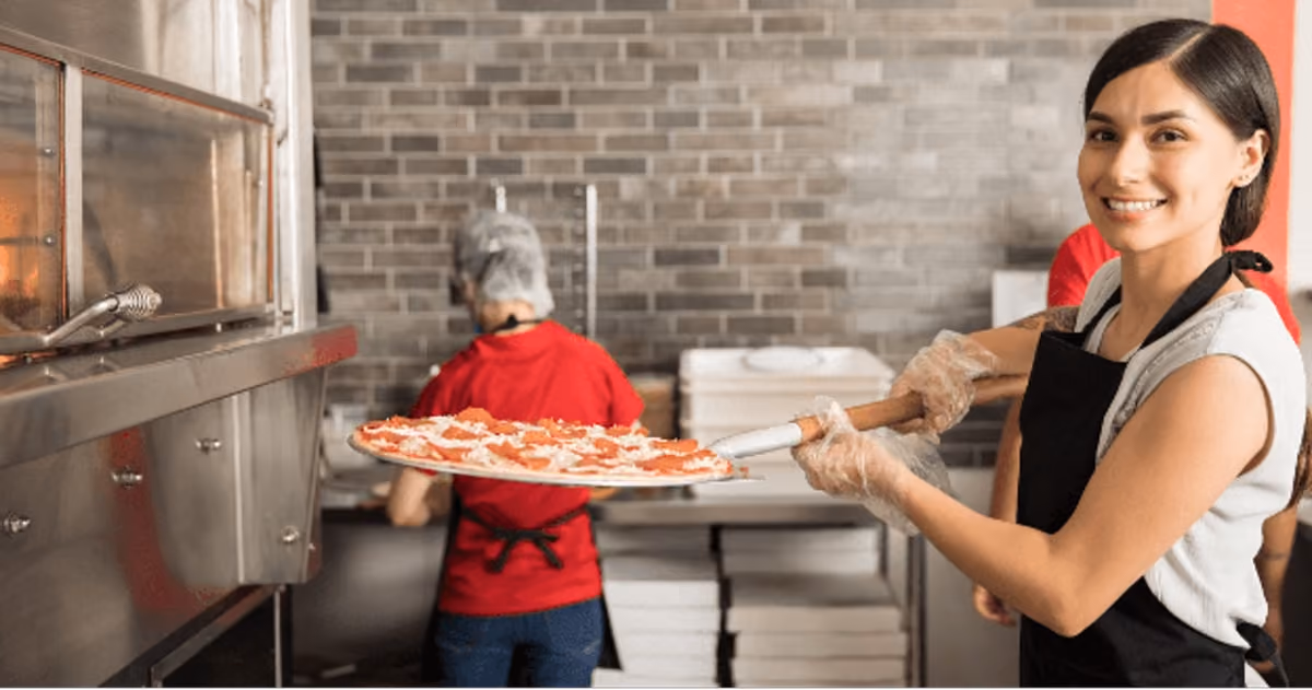 A woman carefully removes a freshly baked pizza from the oven, showcasing her culinary skills and enthusiasm for cooking.