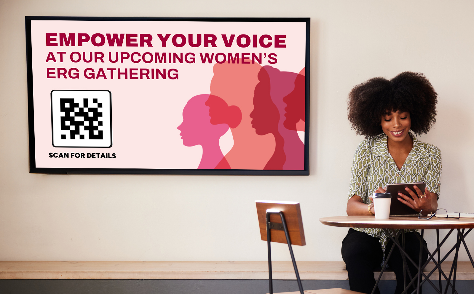 A woman seated in front of a digital sign