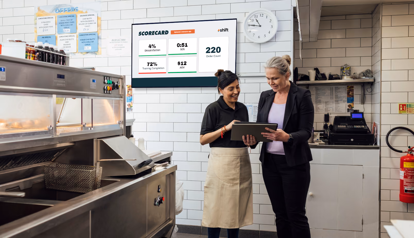 Two women in a QSR restaurant looking at data on a screen