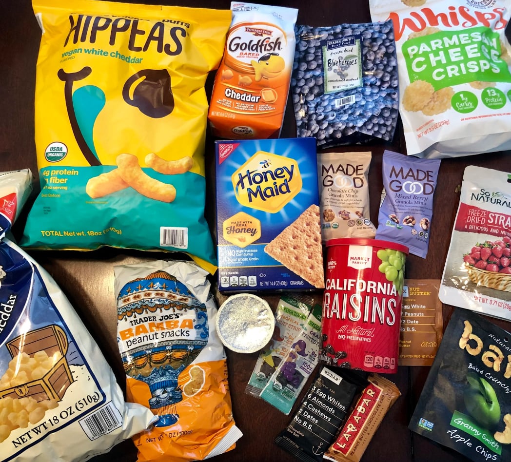 A variety of snacks, including chips, fruits, and candies, are arranged neatly on a table for a gathering.  